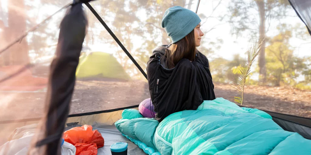 femme au milieu de la nature dans un sac de couchage